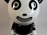 une figurine de panda noir et blanc assise sur une surface blanche