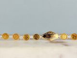 un gros plan d'un bracelet en or orné de pièces de monnaie, posé sur une surface en marbre