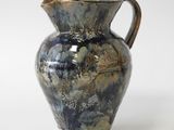 a blue and brown vase sitting on a white surface