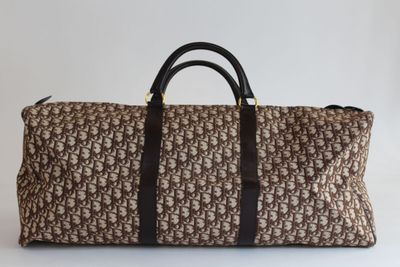 un sac de voyage marron et noir posé sur une surface blanche