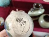 a person holding a ball in their hand in front of some vases