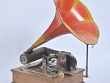un gramophone rouge et jaune posé sur un socle en bois