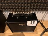 a black amp sitting on the floor next to a pair of microphone stands
