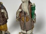 three figurines of a man and a woman standing next to each other