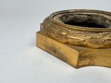 a gold colored candle holder on a white surface