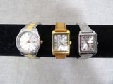 three different watches are displayed on a black display stand