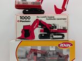 two boxed boxes of toys including a red and black excavator and a red bulldozer