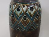 a brown and blue vase sitting on a white surface