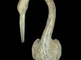 a statue of a bird with a long neck on a black background