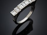 a white gold ring with baguets of diamonds on a black surface