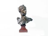 un buste en bronze représentant un jeune homme, posé sur un socle rouge