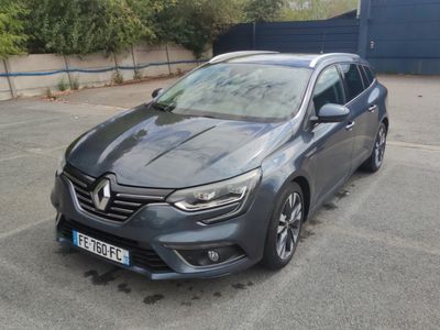 La voiture grise est garée sur le parking à côté du bâtiment.