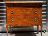 une commode ancienne avec un plateau en marbre, placée au milieu d'une pièce