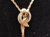 un collier en or orné d'un oiseau, porté par un mannequin
