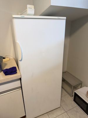 a white refrigerator in the corner of a small kitchen