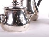 a silver tea pot sitting next to other silver teapots
