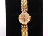 a close up of a gold watch on a black velvet case