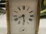 a small gold clock with roman numerals on it