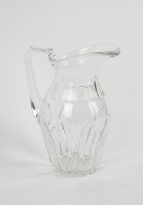 clear glass pitcher sitting on a white surface with a white background
