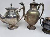 three silver teapots sitting next to each other on a table