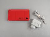 une photo d'une console de jeux Nintendo Wii rouge à côté d'un chargeur