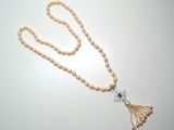 un long collier de perles auquel est suspendu un pompon