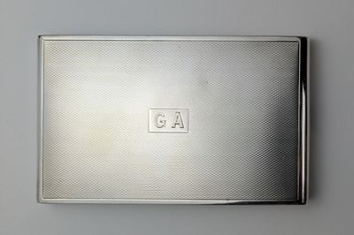 an antique silver cigarette case with a monogram on the front