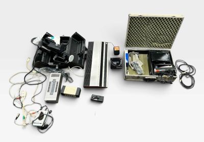 une valise contenant un appareil photo et d'autres appareils électroniques, posée sur une surface blanche