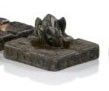 une petite statue de chien posée sur un bloc de pierre, à côté d'une autre statue de chien, plus petite, posée sur un bloc de pierre