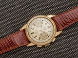 un gros plan d'une montre avec un bracelet marron sur un fond noir