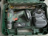 une boîte à outils verte contenant une perceuse et d'autres outils