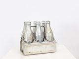 four bottles of soda in a wooden crate on a table