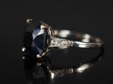 un gros plan d'une bague en saphir et diamants posée sur une surface noire