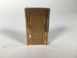 un gros plan d'un briquet doré posé sur une surface blanche