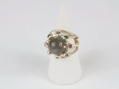 un gros plan d'une bague ornée d'une pierre noire entourée de pierres multicolores