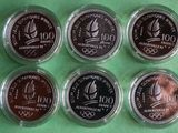 six commemorative coins of the olympic games are displayed on a green surface