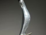 a silver sculpture of a bird on a metal stand