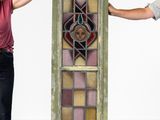 two people standing next to a tall stained glass window in a room