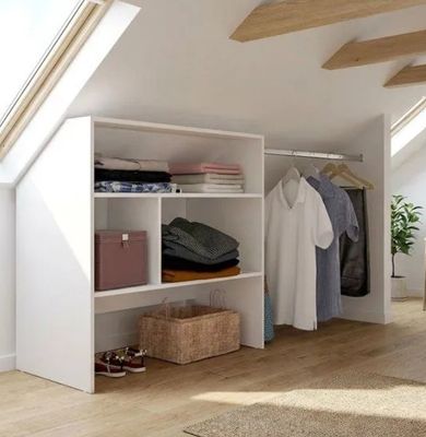 une armoire contenant des vêtements, sur laquelle sont posés d'autres vêtements, dans un loft