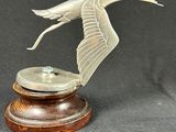 an image of a statue of a bird flying over a wooden base
