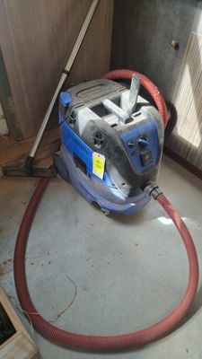 un aspirateur posé sur le sol à côté d'une porte
