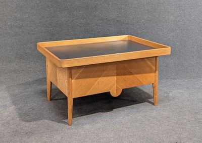 une image représentant une table en bois avec un plateau en verre posée sur une surface grise