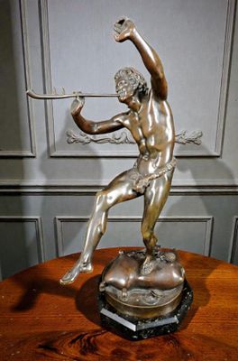 statue en bronze représentant un homme tenant un arc et une flèche, posée sur une table en bois