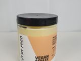 un gros plan sur un pot de masque réparateur vegan posé sur une surface blanche