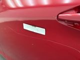 a close up of a red car with a sticker on it