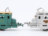 two toy trains sitting next to each other on a white surface