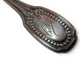 a silver spoon with a picture on it on a white surface
