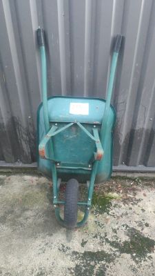 a green wheelbarrow with a sign on the side of it