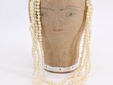 beige mannequin head with white pearls and a chain of pearls