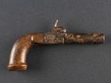 un vieux pistolet avec une poignée en bois sur une surface grise